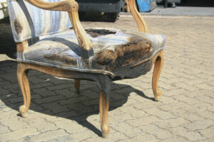 Image of a fire-damaged antique chair awaiting restoration by System Restoration Technologies