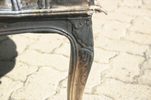 Close-up image of a fire-damaged antique chair awaiting restoration by System Restoration Technologies.